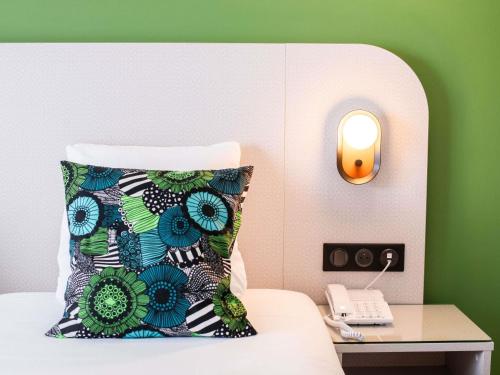 a bed with a pillow and a phone on a table at Ibis Styles Cayenne Centre Amazonia in Cayenne