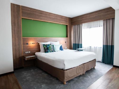 a bedroom with a large bed with a green wall at Ibis Styles Cayenne Centre Amazonia in Cayenne