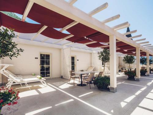 a patio with a red umbrella and a table and chairs at Heritage Grand Perast By Rixos in Perast