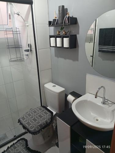 un bagno con un water, un lavandino e uno specchio di Meu Cantinho a Botucatu