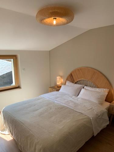a bedroom with a large white bed with a ceiling at OHANA Appartement de charme in Château-Gontier