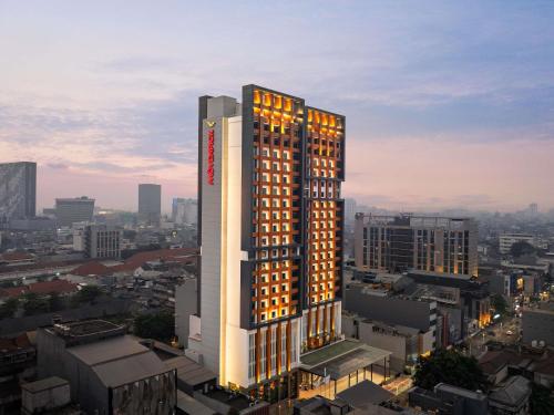 a tall building with lights on in a city at Mövenpick Hotel Jakarta City Centre in Jakarta
