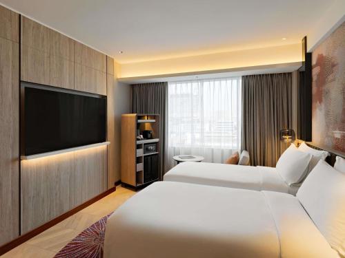 a hotel room with two beds and a flat screen tv at Mövenpick Hotel Jakarta City Centre in Jakarta
