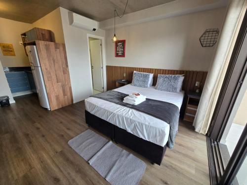 a bedroom with a large bed and a refrigerator at Conforto no Largo do Arouche 77 c Varanda, Lazer e Vista A 250m do Metrô in São Paulo