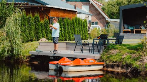 a man standing on a dock next to a boat at Natursee-Chalet, Angeln, Wellness, Spa, Ponyhof in Twist