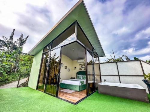 a small guest house with a large window and green grass at Villas Malu View Domos modernos con vista al Volcán Arenal in El Castillo de La Fortuna