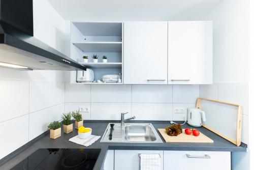 a kitchen with white cabinets and a sink at BellaBene modernes Studioapartment in zentraler Lage, Arbeitsplatz, Parkplatz in Pforzheim