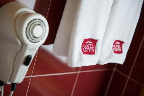 a towel hanging in a bathroom with a hotel kestation sign at Hotel Astra in Livigno