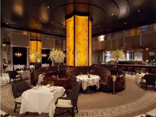 a restaurant with white tables and chairs and a bar at Trump International Condo Hotel in Las Vegas