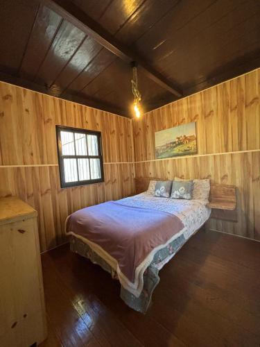 a bedroom with a bed in a wooden room at Casa de Campo da Vó in Urupema