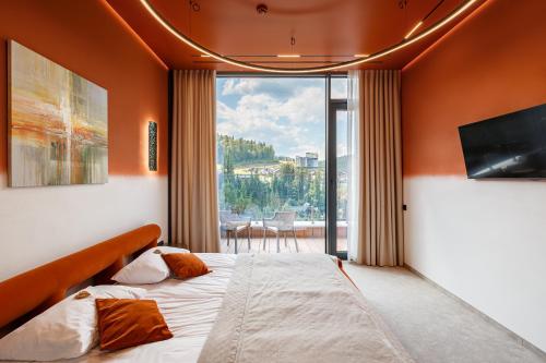 a bedroom with a bed and a large window at Tavel Hotel & SPA in Bukovel