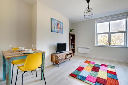 a living room with a table and yellow chairs and a rug at Phoebe’s - Ellinbrook Apartments in Hunstanton