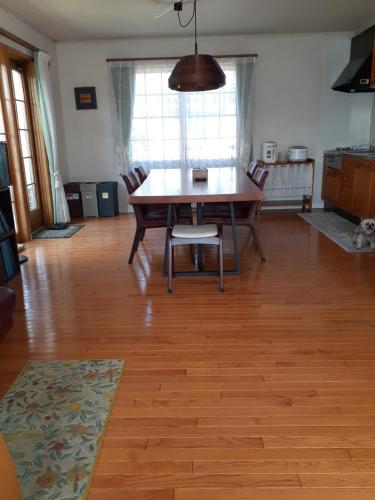 a dining room with a table and chairs on a wooden floor at ゲストハウス苫小牧 ファミリールーム in Tomakomai