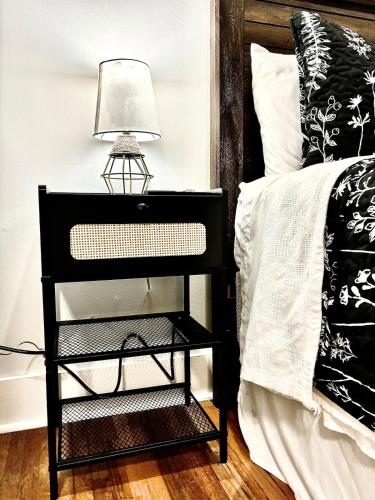 a black nightstand with a lamp on it next to a bed at The Crescent House in Hutchinson