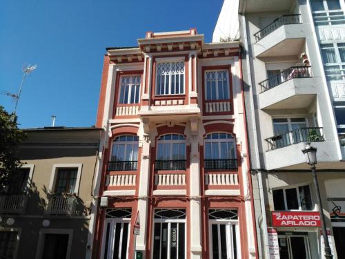 een roze gebouw met ramen aan een stadsstraat bij Apartamentos San Roque in Ribadeo
