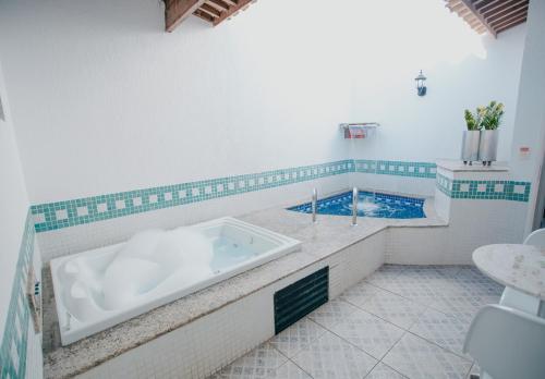 a bathroom with a tub and a swimming pool at Vert Motel Parnamirim in Parnamirim