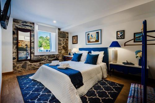 a bedroom with a large bed with blue pillows at Trilogia in Lousã