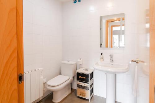 a white bathroom with a toilet and a sink at La Caseta de Cercs, Barbecue y Pet Friendly in Sant Jordi de Cercs