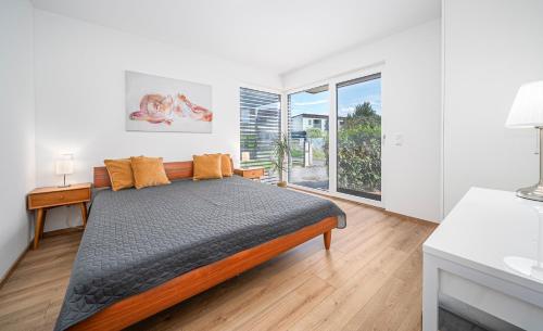 a bedroom with a bed and a large window at Moderner Bungalow in Seenähe in Hard