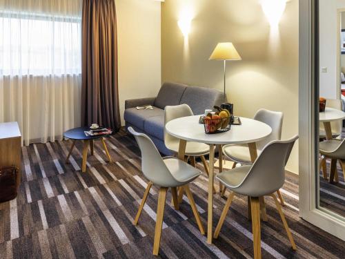 a living room with a couch and a table and chairs at Mercure Agen Centre in Agen