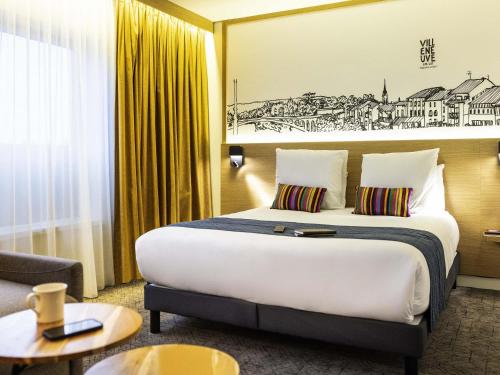 a hotel room with a large bed and a couch at Mercure Agen Centre in Agen