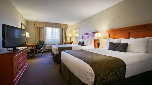 a hotel room with two beds and a flat screen tv at Best Western Plus Kennewick Inn in Kennewick