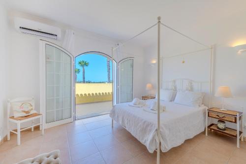 une chambre blanche avec un lit et une grande fenêtre dans l'établissement Villa Monte da Torre, à Loulé