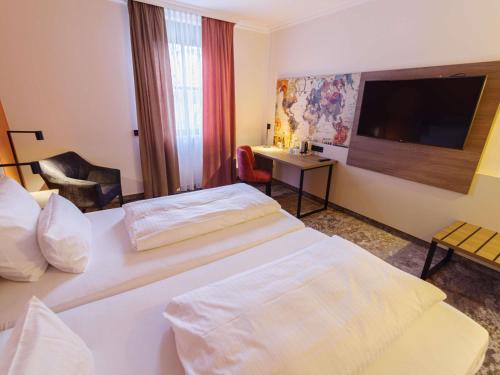 a hotel room with two beds and a flat screen tv at Atomis Hotel Munich Airport by Mercure in Oberding