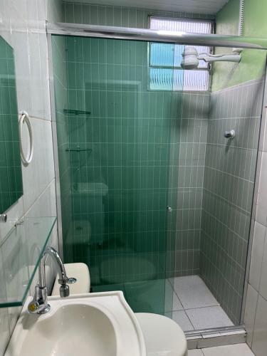 a green tiled bathroom with a toilet and a shower at Apto Natureza Verde Manauara II in Manaus