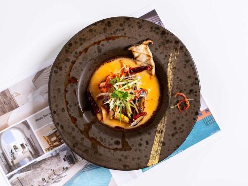 a plate of food in a bowl on a table at Andaman Beach Hotel Phuket - Handwritten Collection in Patong Beach