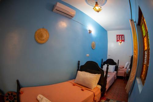 a room with two beds and a blue wall at Riad Misk Fez in Fès