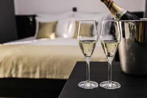 dos copas de vino blanco en una mesa junto a una cama en Garni Hotel Zen en Niš