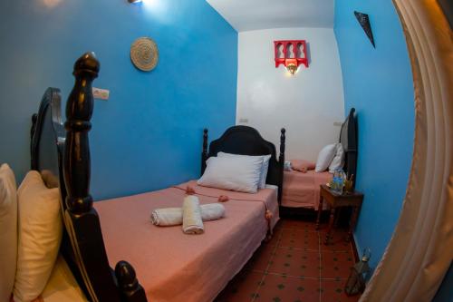 two beds in a room with blue walls and a mirror at Riad Misk Fez in Fès