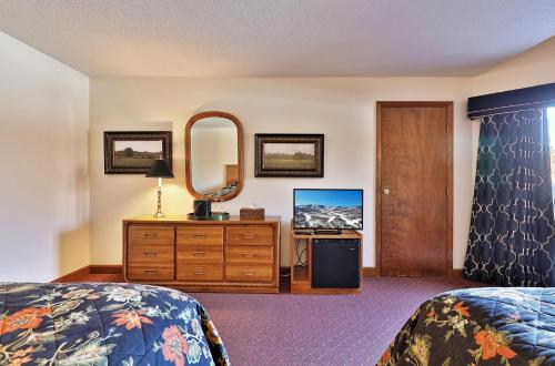 a bedroom with two beds and a mirror and a dresser at Greenbrier Inn Killington in Killington