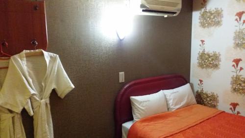 a small bedroom with a bed and a light on the wall at Nakwon Arcade Sky Motel in Seoul