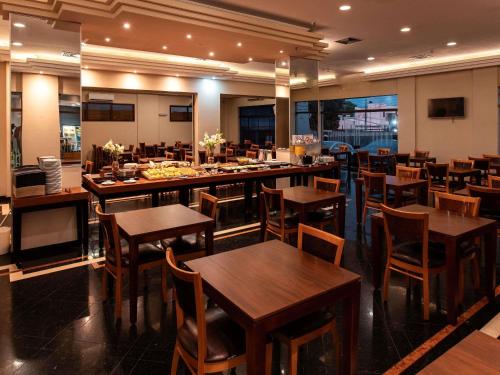 a restaurant with wooden tables and chairs and a bar at ibis Styles Presidente Prudente Portal D'Oeste in Presidente Prudente