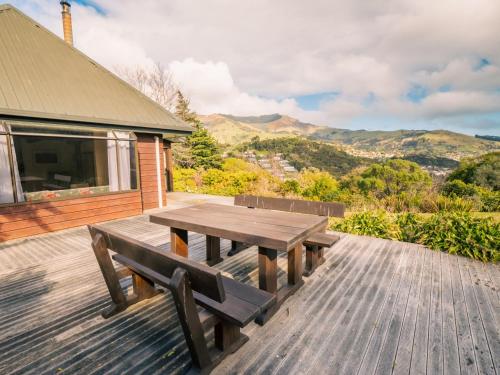 アカロアにあるRelaxed Kiwi Bach Over Akaroa Harbour - Port Watchの山々を背景にしたデッキの木製ピクニックテーブル