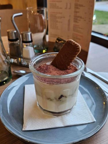 a cup of dessert with a cookie on top on a plate at ibis Douai Dechy in Dechy