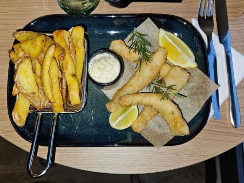 a plate of food with french fries and lemon wedges at ibis Douai Dechy in Dechy