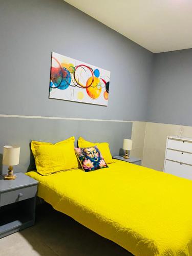 Un dormitorio con una cama amarilla y una pintura en la pared en Large 1 bedroom Apt with sofa bed 6 min walk from the beach, en Santa Maria