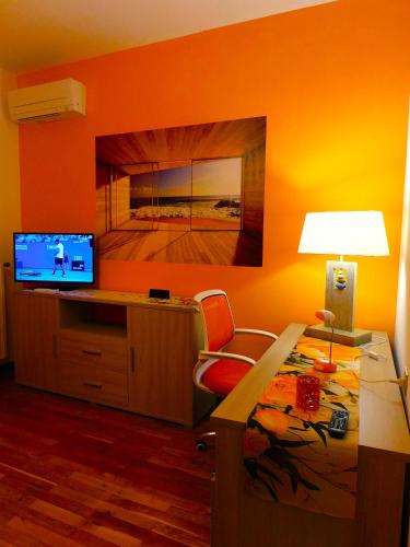 a bedroom with an orange wall with a desk and a television at LUKAS HOME CON IL CUORE Appartamento 3 camere al piano terra e appartamento 1 camera in taverna in Merone