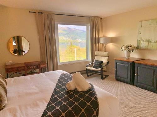 a bedroom with a bed and a window and a chair at Le Belvedère Mont-Tremblant in Mont-Tremblant