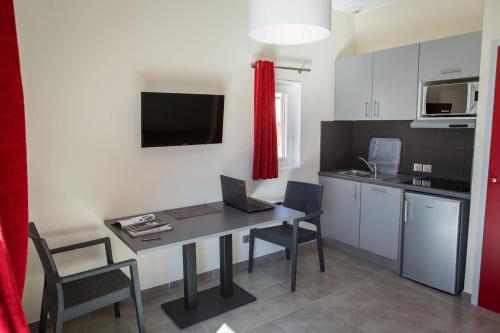 a kitchen with a table with a laptop on it at SOWELL RESIDENCES Les Perles du Golfe de Saint-Tropez in Grimaud