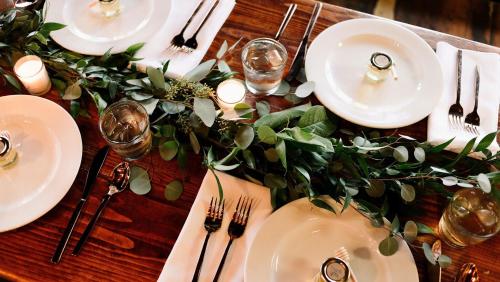 a wooden table topped with white plates and silverware at Kimpton Mirador Pacific Grove Monterey by IHG in Pacific Grove