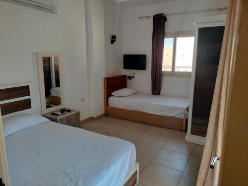 Dahab Hills Villa Resort في دهب: غرفة نوم بسريرين ونافذة وتلفزيون