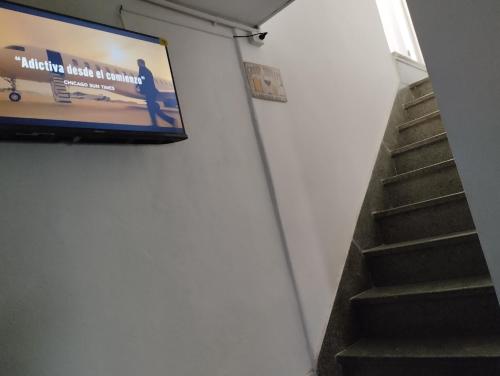 un televisor colgado en una pared junto a una escalera en Casa lajas, en Villa María