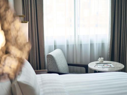 a hotel room with a bed and a table and a chair at Novotel Singapore on Kitchener in Singapore