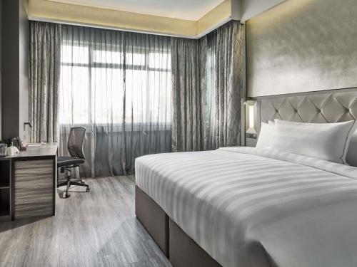 a hotel room with a large bed and a desk at Novotel Singapore on Kitchener in Singapore
