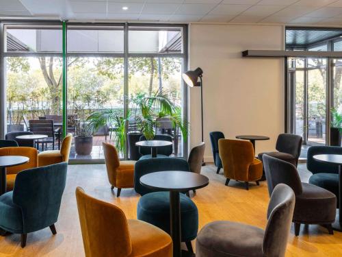 a waiting room with tables and chairs and windows at Ibis Styles Paris Saint Denis Pleyel in Saint-Denis