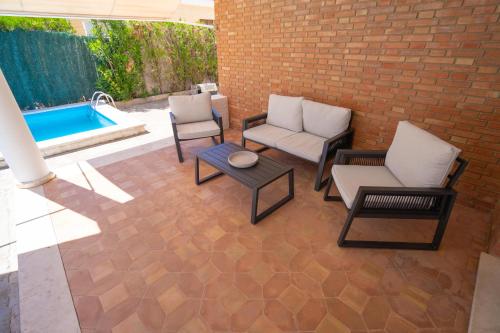 Un patio con sillas y una mesa y una piscina. en Urbasur Villa Islantilla Golf, en Isla Cristina